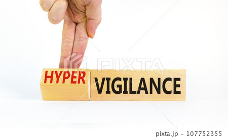 Vigilance or hypervigilance symbol. Concept words Vigilance Hypervigilance on wooden blocks. Beautiful white background. Psychologist hand. Psychology vigilance hypervigilance concept. Copy space. 107752355
