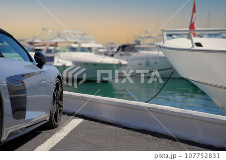 Luxury sports car on the background of yachts. Luxury sports car on the background of yachts. 107752831