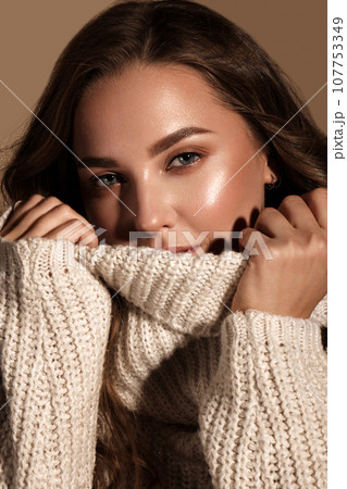 Beautiful young girl with gentle make-up in warm sweater and long straight hair. Beauty face. 107753349