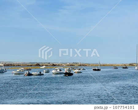 Canal de Tavira . Small boat cruising tranquil green river. 107754101