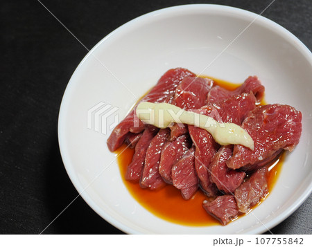 おろしにんにくを乗せてタレをかけた赤身の馬刺し 107755842