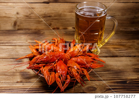 Boiled crayfish and mug of beer on a wooden table Boiled crayfish and mug of beer on a wooden table 107758277