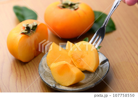 とっても甘い秋の味覚 皿に盛り付けた 柿をフォークでつまむ フルーツ （テーブルバック）柿の実 かき 107758550