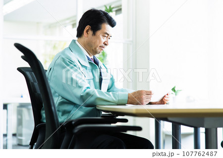 オフィスの会議室で会議をする作業服を着たミドルのビジネスマン 107762487