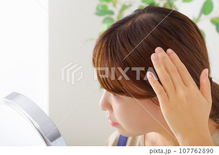 髪の毛を気にする仕草をしている女性 107762890