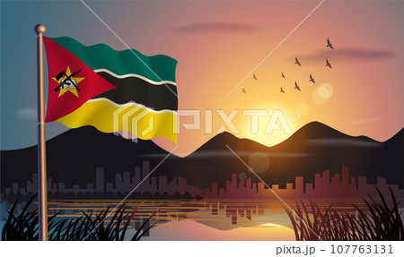 Mozambique flags flutter against the sunrise sky and beautiful lake. Celebrating national day and travel tourism 107763131