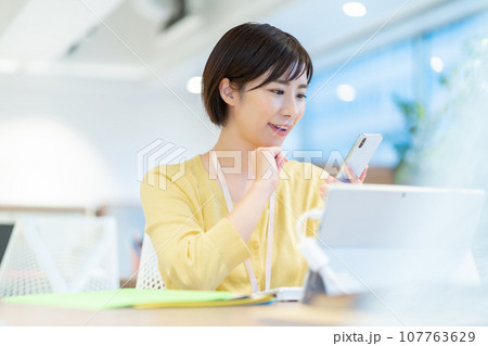 スマホを操作するOL デスクワークをする女性社員 スマホを操作するOL デスクワークをする女性社員 107763629