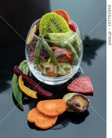 Different colorful dried fruits and vegetables in the glass. Crispy mixed veggies and fruits. Different colorful dried fruits and vegetables in the glass. Crispy mixed veggies and fruits. 107763948