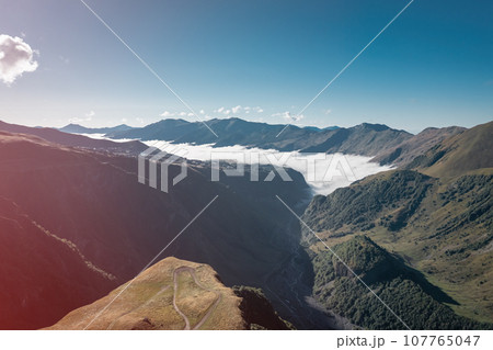 Beautiful morning landscape of the Caucasus mountains with clouds in the valley Beautiful morning landscape of the Caucasus mountains with clouds in the valley 107765047