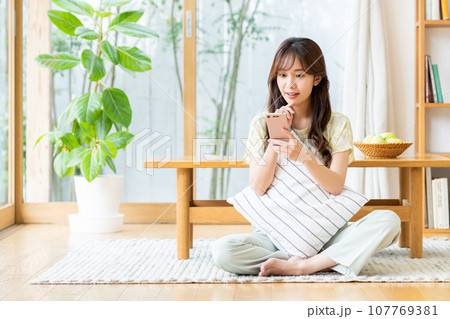 リビングでスマホを見る若い女性 リビングでスマホを見る若い女性 107769381
