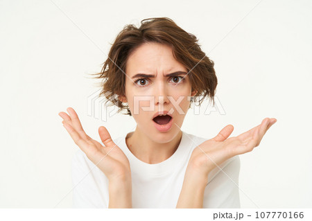Close up of shocked brunette woman, shrugging and looking disappointed, posing over white studio background 107770166