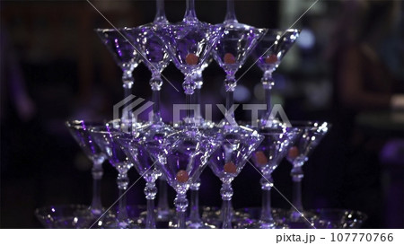 Pyramid from glasses of champagne on wedding party. Clip. Champagne pyramid for wedding party. Waiter pouring champagne in wineglasses at pyramid Pyramid from glasses of champagne on wedding party. Clip. Champagne pyramid for wedding party. Waiter pouring champagne in wineglasses at pyramid 107770766