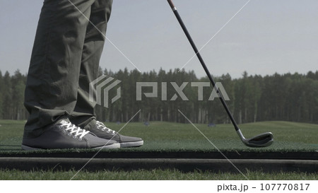 Golfer Hitting Ball with Club on Beautiful Golf Course. Golfer hits an fairway shot towards the club house. Man hitting driver on a golf course in the sun. Professional male golf player Golfer Hitting Ball with Club on Beautiful Golf Course. Golfer hits an fairway shot towards the club house. Man hitting driver on a golf course in the sun. Professional male golf player 107770817