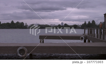 Side view of a handsome man in walking at the lake pier. Silhouette of man on the old wooden bridge natural landscape sunny lake background 107771003