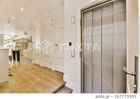 a kitchen and living room in a house with white walls, hardwood flooring and stainless steel door handles on the doors a kitchen and living room in a house with white walls, hardwood flooring and stainless steel door handles on the doors 107773303