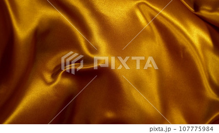 Smooth Elegant Golden Satin Cloth, Close-up. Texture of flying fabric. 107775984