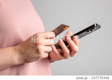 Berlin, Germany October 6 2023 Hands holding mobile phone and bank card, paying online with smartphone 107776346