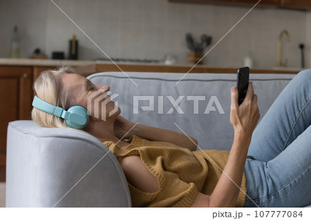 Peaceful smartphone user woman in wireless headphones listening to music Peaceful smartphone user woman in wireless headphones listening to music 107777084