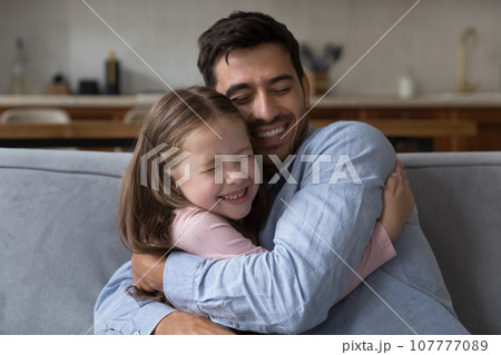 Excited little kid girl tightening beloved daddy with cheek touch 107777089