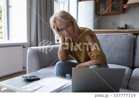 Concerned mature worried homeowner woman checking bills for payment Concerned mature worried homeowner woman checking bills for payment 107777119