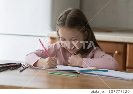 Happy cute little kid girl drawing in colored pencils Happy cute little kid girl drawing in colored pencils 107777120