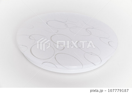 Large round ceiling lamp with a pattern on a white surface. Large round ceiling lamp with a pattern on a white surface. 107779187