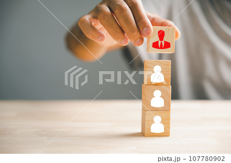Close-up shot of hand selecting man people icons on cube wooden toy blocks stacked. Illustrates the concept of employee management and the importance of human resources in business success. Close-up shot of hand selecting man people icons on cube wooden toy blocks stacked. Illustrates the concept of employee management and the importance of human resources in business success. 107780902
