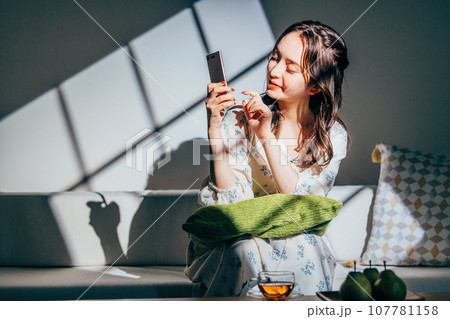 ソファでスマホを操作する女性 ソファでスマホを操作する女性 107781158