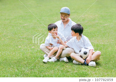 新緑の公園でサッカーボールを取り合って遊ぶ男兄弟とパパ・父親(家族・ファミリー) 新緑の公園でサッカーボールを取り合って遊ぶ男兄弟とパパ・父親(家族・ファミリー) 107782859