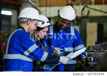 Team worker wearing uniform safety brainstorming holding blueprint plan work management 107782944