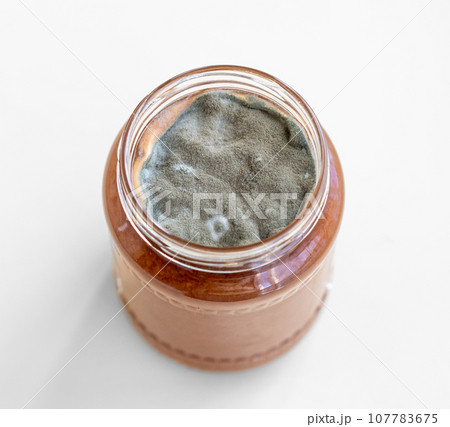 Open jar with sweet jam and mold on a white background. Mold in a jar of raspberry jam. Hazardous to health. Open jar with sweet jam and mold on a white background. Mold in a jar of raspberry jam. Hazardous to health. 107783675