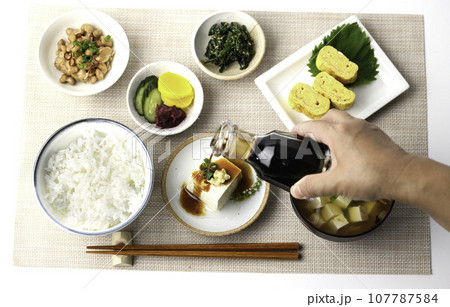 和食の朝ごはん 俯瞰撮影(冷奴にお醤油をかける)納豆、味噌汁 卵焼き めざし 漬物 日本食 和食の朝ごはん 俯瞰撮影(冷奴にお醤油をかける)納豆、味噌汁 卵焼き めざし 漬物 日本食 107787584