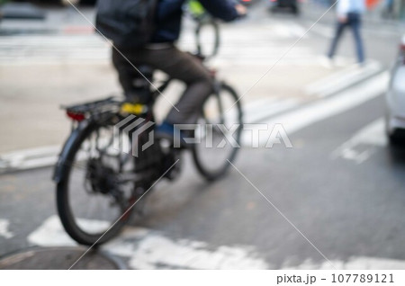 Defocused food delivery service bike rider on city street 107789121