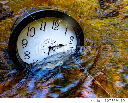 A large clock half submerged in a beautiful flowing stream A large clock half submerged in a beautiful flowing stream 107789130