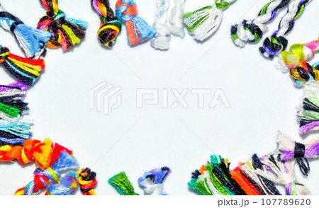 Frame made of woven colorful handmade ties of bracelets Frame made of woven colorful handmade ties of bracelets 107789620