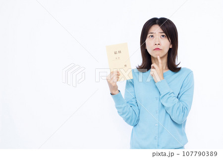 白い背景の前で給料袋を持って悩んでいる30代の女性 107790389