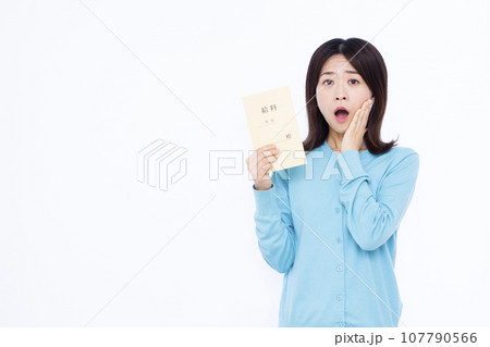 白い背景の前で給料袋を持って驚いている30代の女性 白い背景の前で給料袋を持って驚いている30代の女性 107790566