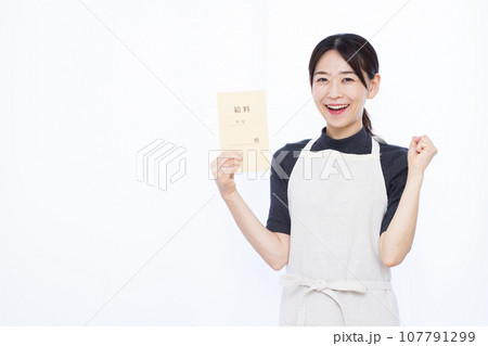 白い背景の前で給料袋を持ってガッツポーズをしている30代の主婦 107791299