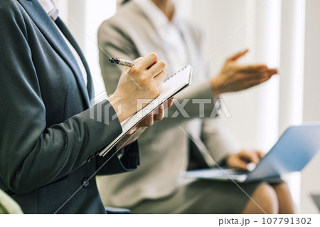 打ち合わせ・商談でメモをとる女性 107791302