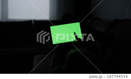 Man at home lying on a couch with tablet pc with green screen 107794534