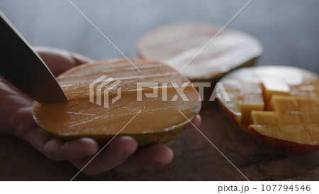 Man cut ripe big mango on olive wood board 107794546