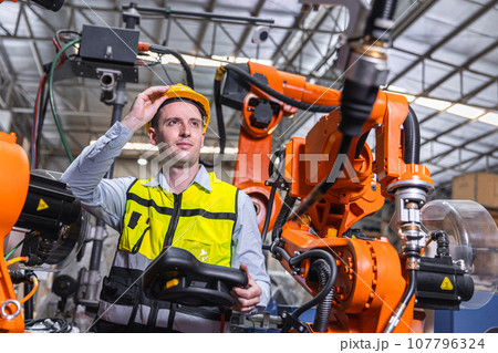Smart modern engineer male using modern robot technology. Robotic welding arm setup in automation production process in factory Smart modern engineer male using modern robot technology. Robotic welding arm setup in automation production process in factory 107796324