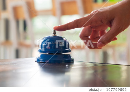 Female Press to Ringing a Bell for Call Customer Service at the Service Counter Female Press to Ringing a Bell for Call Customer Service at the Service Counter 107799892