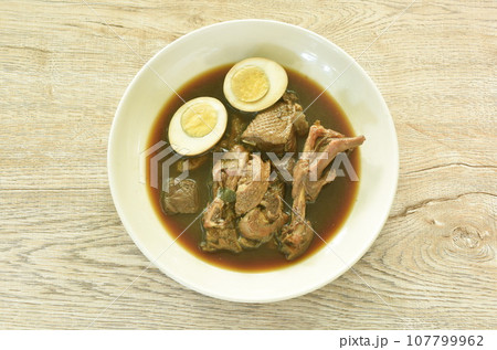 boiled half cut egg with braised duck meat and foot in Chinese herb brown soup on plate   107799962