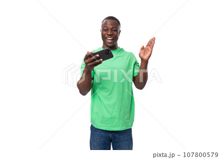 A 30-year-old American man dressed in a light green basic T-shirt is watching a video on a A 30-year-old American man dressed in a light green basic T-shirt is watching a video on a 107800579