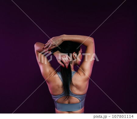 Back view of a young athlete stretching her arms before workout 107801114