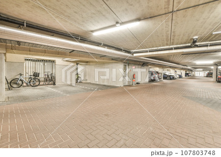 an underground parking area with bikes parked in the garages on either side of each other cars and one car 107803748