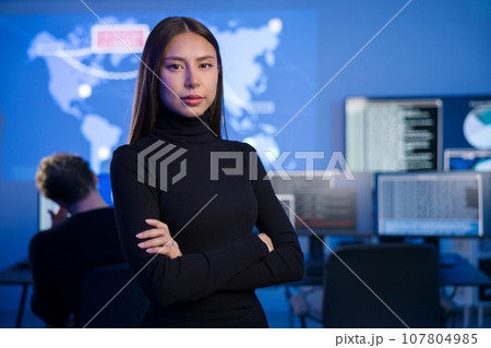 Female Cybersecurity Analyst or Manager in large Cyber Security Operations Center SOC handling Threats 107804985