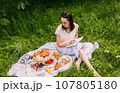 Beautiful woman on picnic. She smiles, eats strawberries and enjoys summer. 107805180