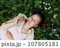 Beautiful woman with natural beauty without makeup lies in the grass in summer 107805181